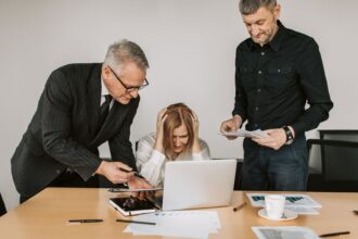 Trois professionnels en réunion tendue autour d'un ordinateur portable.