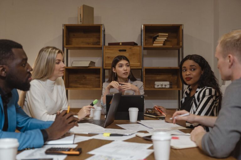 Groupe de professionnels discutant stratégies dans un cadre bureau moderne.