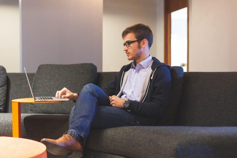 Jeune entrepreneur assis sur un canapé, travaillant avec un bloc-notes.
