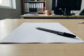 Feuille blanche et stylo noir sur une table de bureau en bois, lumière naturelle.