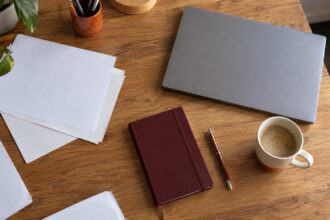 Table de travail avec documents, bloc-notes, ordinateur portable fermé et tasse de café