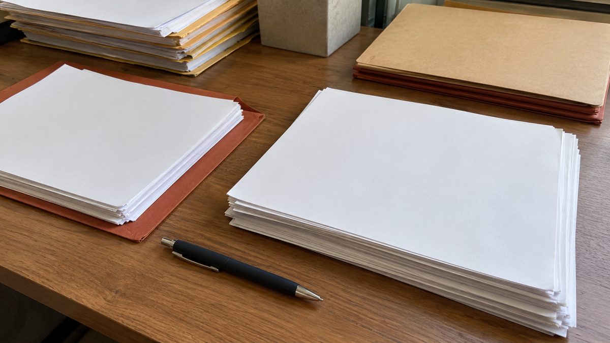 Table de travail avec documents imprimés, dossiers et stylo, lumière naturelle